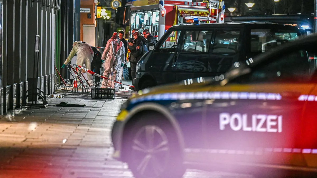 Mitarbeiter der Spurensicherung und der Polizei stehen im abgesperrten Bereich in der Nähe des Münsterplatzes. Die Polizei hat eine Geiselnahme am Ulmer Münsterplatz mit Hilfe von Schusswaffengebrauch beendet. (zu dpa: „Haftbefehl gegen mutmaßlichen Geiselnehmer von Ulm»)