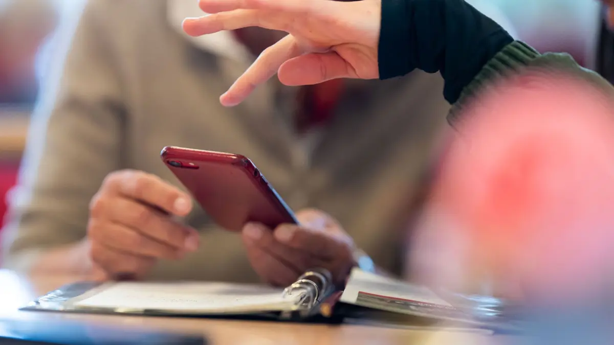 Eine Beraterin beantwortet während der Smartphone–Sprechstunde für Senioren Fragen rund um ein iPhone. Seit 2021 bietet die Caritas Sprechstunden an, in denen ältere Menschen Hilfe bei Problemen mit dem Handy bekommen. Der Verband sucht dringend nach weiteren Beratern für diese Sprechstunden. (zu dpa: „«Nachhilfe“ für das Smartphone: Junge Menschen unterstützen Senioren»)
