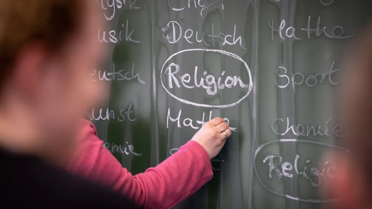 ILLUSTRATION — Eine Lehrerin schreibt mit Kreide einen Stundenplan mit Religionsunterricht an eine Tafel. (zu dpa: „Nur noch zwei von drei Schulkindern besuchen Religionsunterricht»)