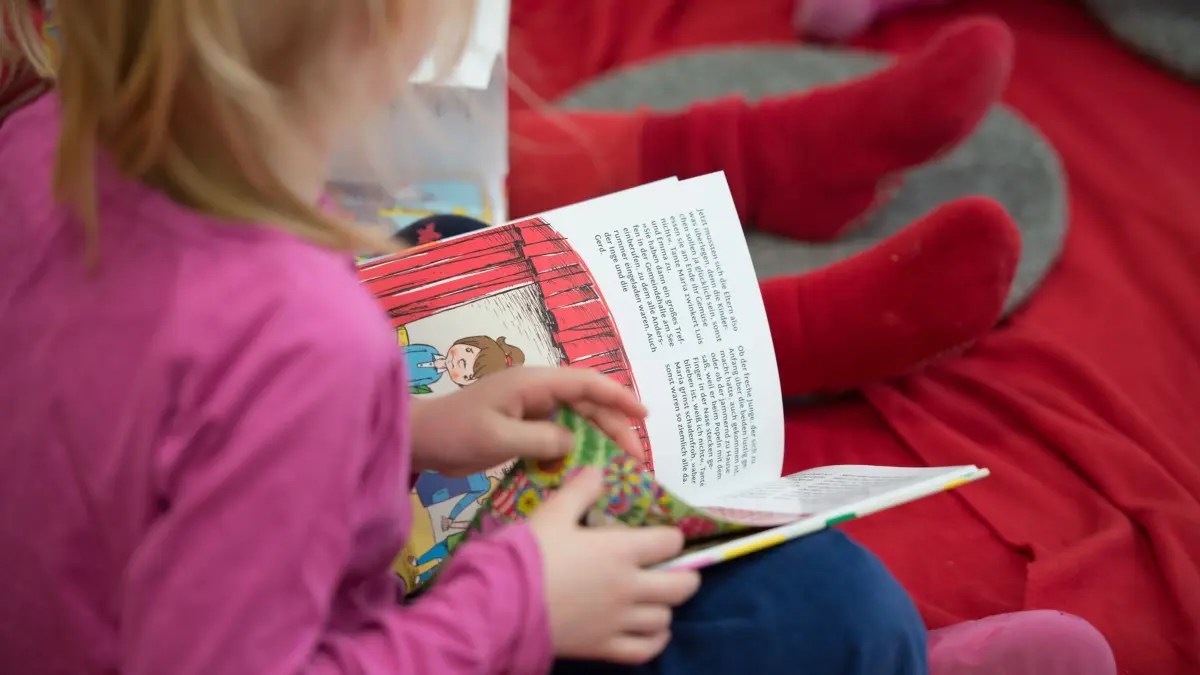 ARCHIV — ILLUSTRATION — Ein Mädchen liest am 04.03.2015 in einer Kita in Hamburg in einem Buch. Foto\ Daniel Reinhardt/dpa +++(c) dpa — Bildfunk+++ (zu dpa: „Umfrage in NRW: Schwache Bedingungen bremsen Sprachförderung in Kitas»)