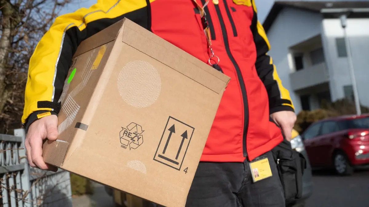 Wenn der Empfänger nicht da ist, können Paketboten das Paket auch beim Nachbarn abgeben.
15.12.2021, Hessen, Ober-Ramstadt: Ein DHL-Mitarbeiter trägt ein Paket unter seinem Arm. (Zu dpa "Zusteller tragen vor Weihnachten Millionen Päckchen aus") Foto: Sebastian Gollnow/dpa +++ dpa-Bildfunk +++