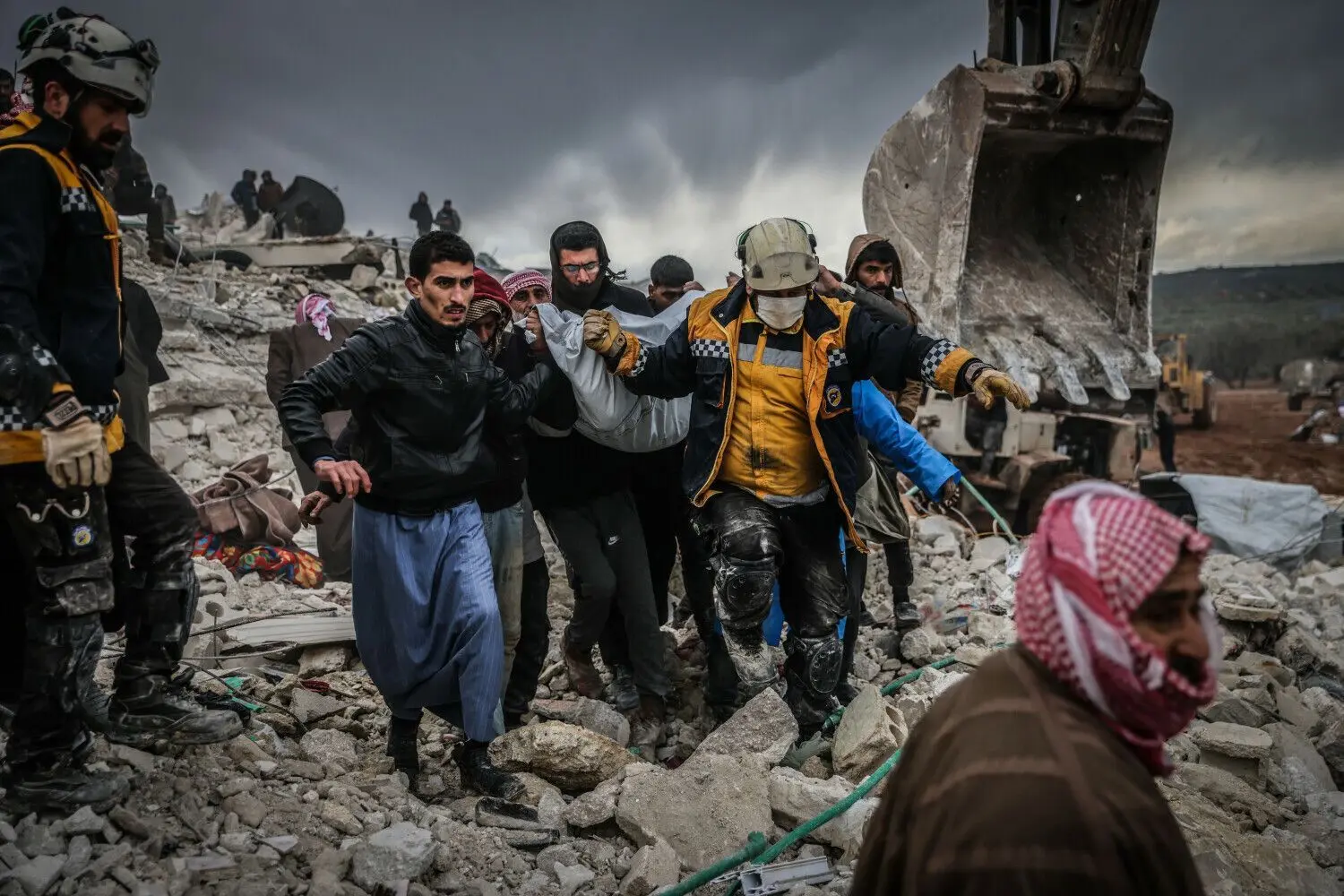 Zivilisten und Mitglieder des syrischen Zivilschutzes führen Such- und Rettungsmaßnahmen in den Trümmern eines zerstörten Gebäudes durch.⇥