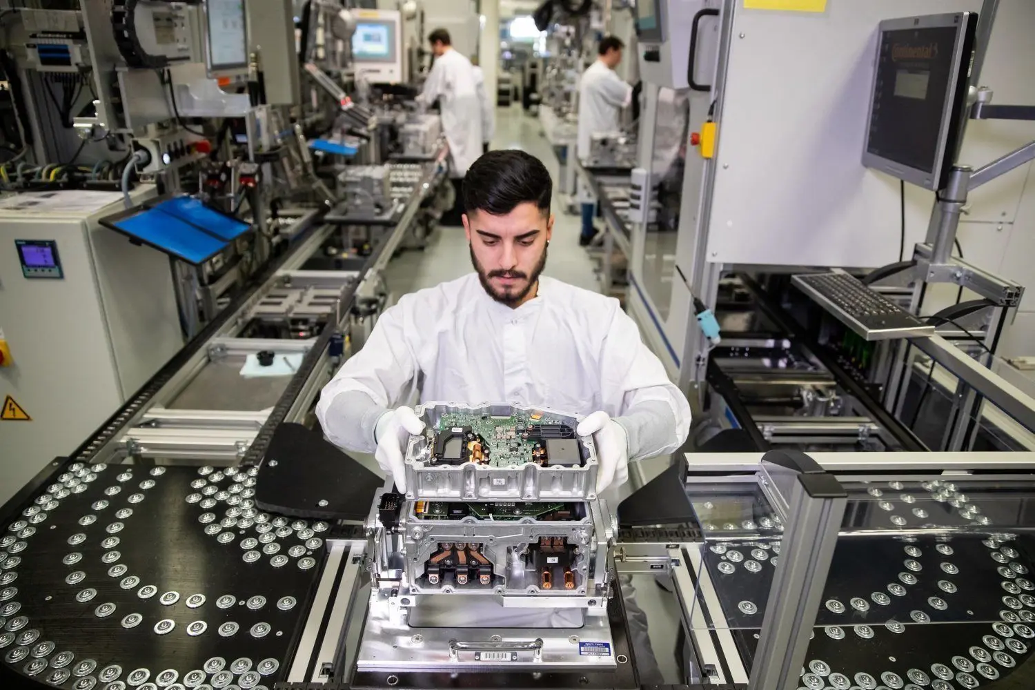 Weißes Oberteil und Handschuhe: Der Autobau ändert sich radikal. Hier wird an der Elektrik gearbeitet. ⇥