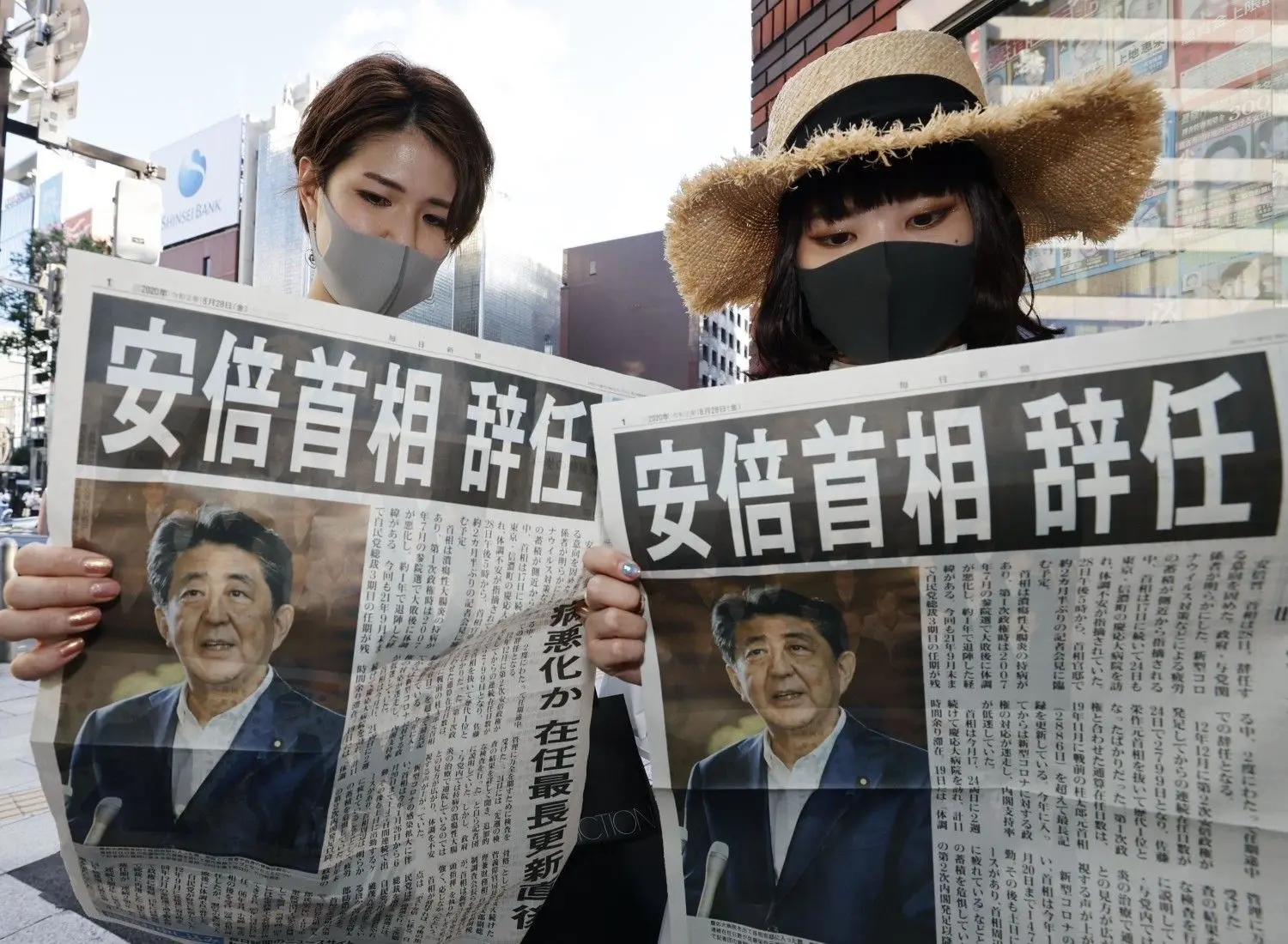 Zwei Frauen mit Mundschutz lesen die Sonderausgabe einer Zeitung. Japans rechtskonservativer Regierungschef Abe hat wegen gesundheitlicher Probleme seinen Rücktritt angekündigt.⇥