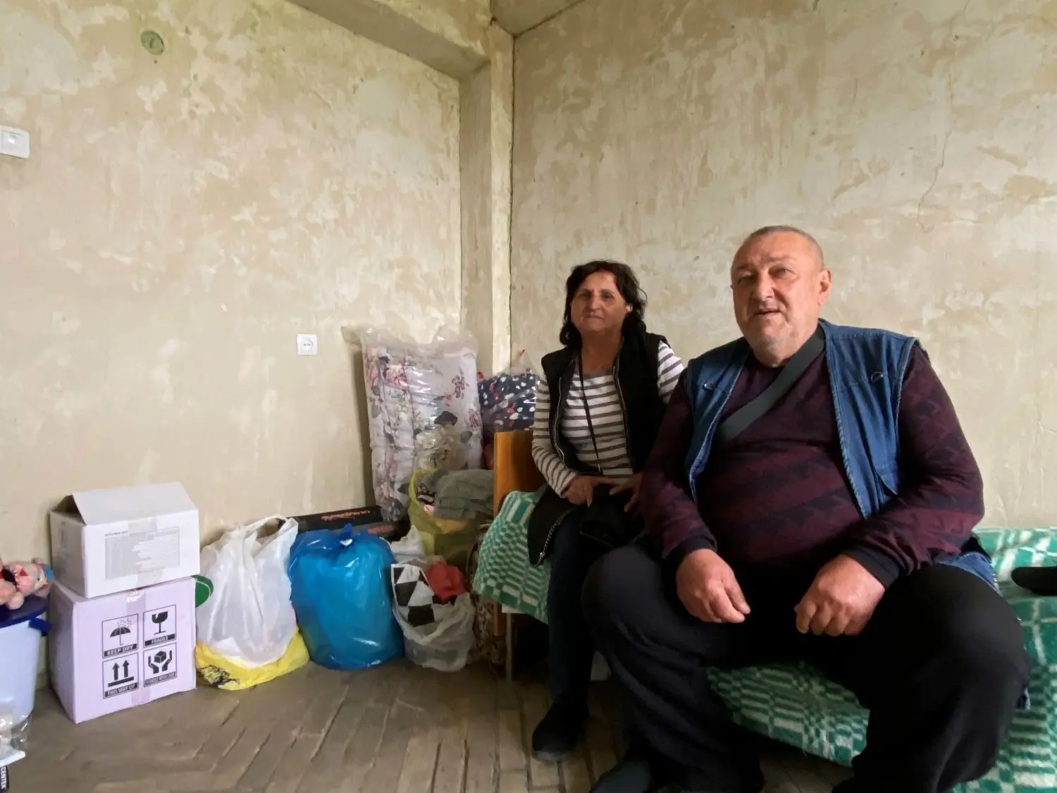 Edvard und Eleanora Faramazyan, die aus Bergkarabach geflüchtet sind, in einer Wohnung in Masis. Ihr ganzes Hab und Gut steckt in den Tüten neben ihnen.⇥