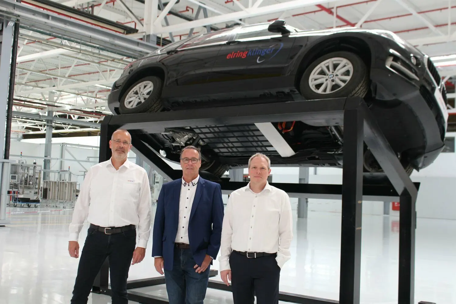 Gunnar Deichmann (Batterie), Jürgen Weingärtner (Drivetrain) und Werkleiter Frank Schaible (von links) stellen den neuen Standort von Elring-Klinger in Neuffen vor. Im Hintergrund ein Wagen mit neuer Antriebs-Technologie.⇥