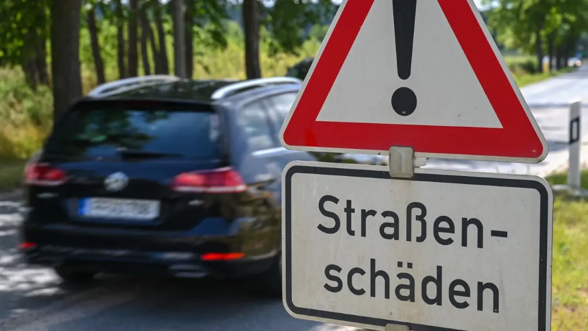Ein Schild mit der Aufschrift «Straßenschäden» ist an einer Straße in Frankfurt (Oder) zu lesen. Es sind noch nicht mal alle Winterschäden an Brandenburgs Straßen beseitigt, da sorgt Sommerhitze für weitere Probleme.
02.07.2021, Brandenburg, Frankfurt (Oder): Ein Schild mit der Aufschrift «Straßenschäden» ist an einer Straße zu lesen. Es sind noch nicht mal alle Winterschäden an Brandenburgs Straßen beseitigt, da sorgt Sommerhitze für weitere Probleme. Geld für Straßensanierungen steht zur Verfügung, allerdings reicht das nicht überall und Förderprogramme sind rar. Foto: Patrick Pleul/dpa-Zentralbild/ZB - Honorarfrei nur für Bezieher des Dienstes ZB-Funkregio Ost +++ ZB-FUNKREGIO OST +++