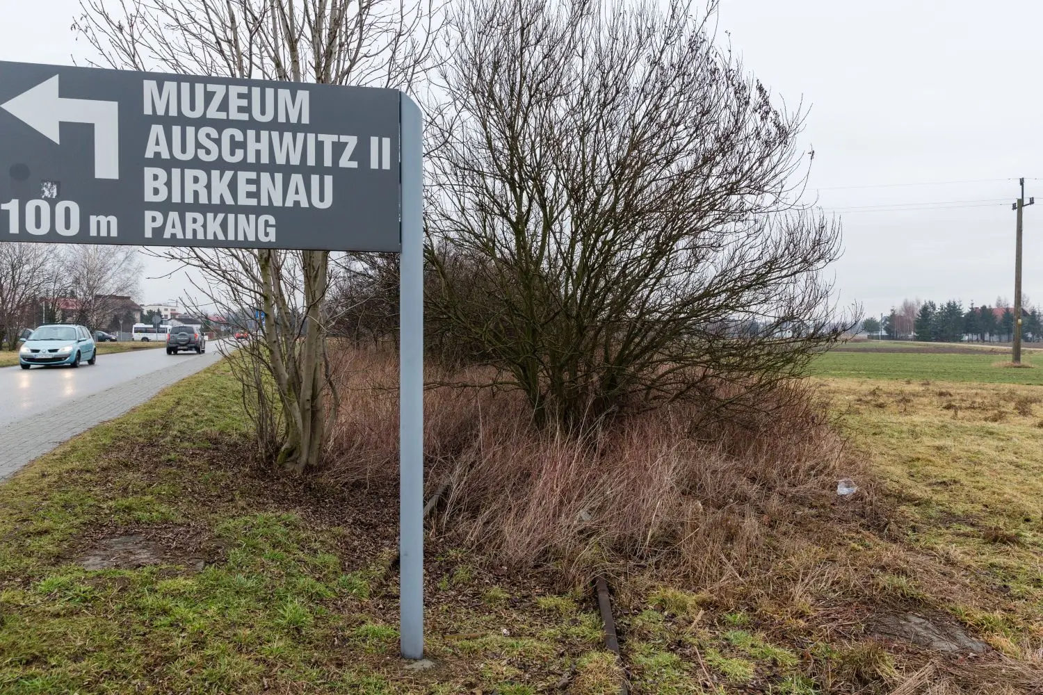 Zufahrt zum neuen Besucherzentrum am Vernichtungslager Auschwitz II. Der Pfosten steht im Gleisbett der Eisenbahnzufahrt ins Lager. ⇥