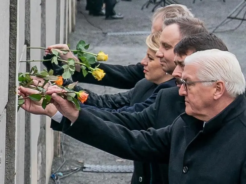 Bundespräsident Frank-Walter Steinmeier (r-l), und die Präsidenten Janos Ader (Ungarn), Andrzej Duda (Polen), Zuzana Caputova (Slowakei) und Milos Zeman (Tschechien) stecken Blumen in die Hinterlandmauer.