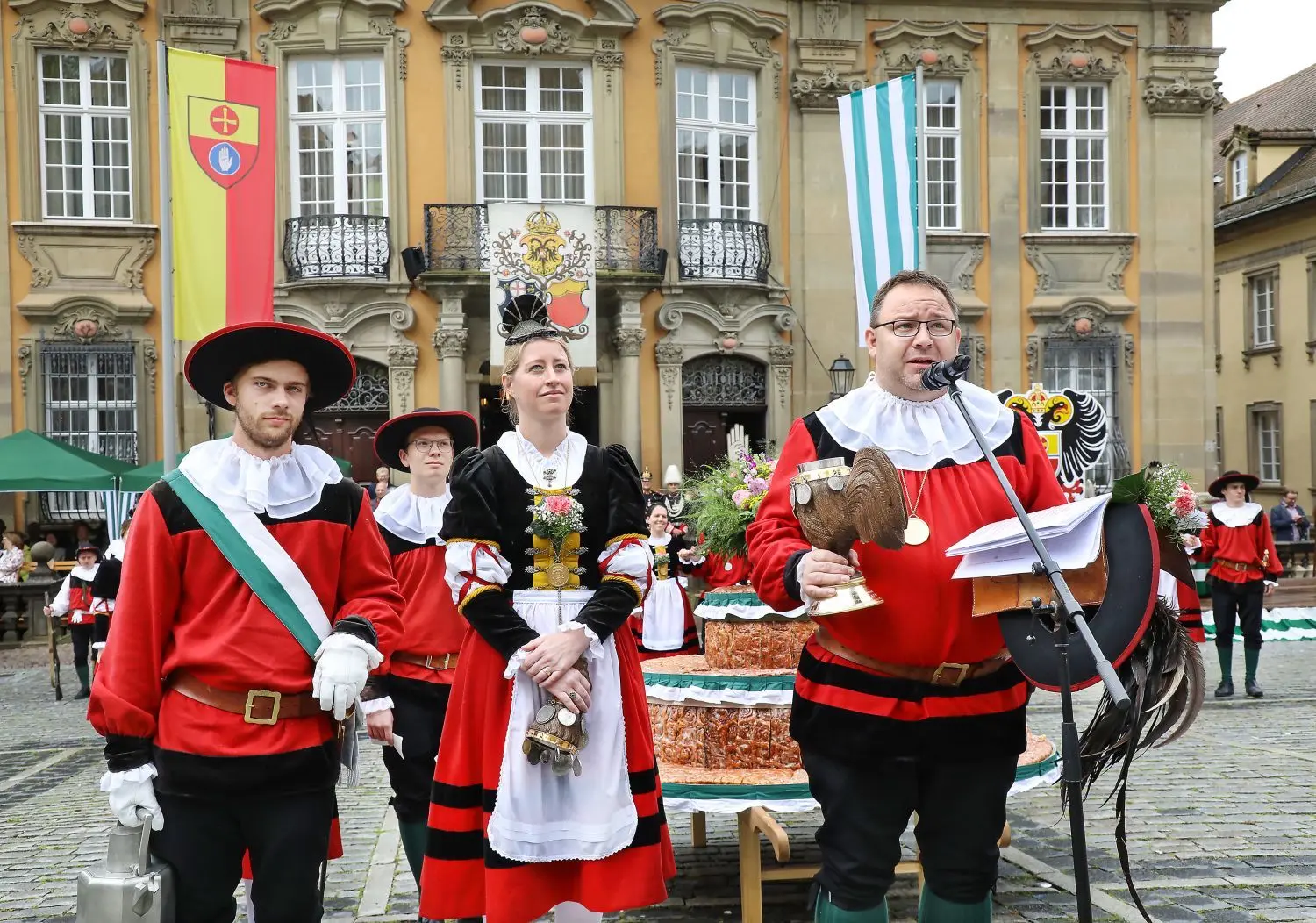 Am Sonntag ist es beim Kuchen- und Brunnenfest Tradition, dass der Erste Hofbursche und weitere Sieder ihre Trinksprüche aufsagen. Stefan Ebert (rechts) reimt etwas zur Bierpreisbremse. Mit dabei sind Erste Tänzerin Anita Röger und Kannenträger Jan Schupp.⇥