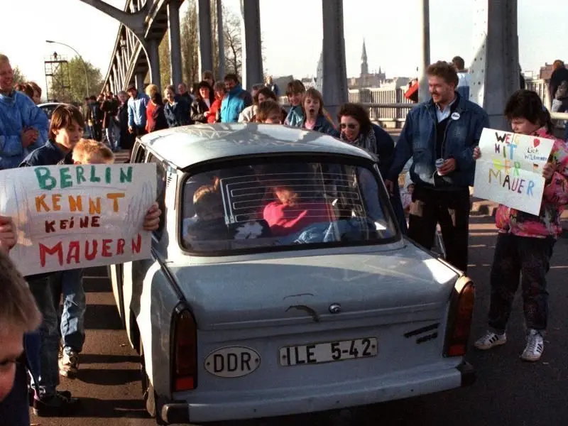Mit selbstgemalten Plakaten wird dieser Trabi am 10. November auf der berühmten Glienicker Brücke von den West-Berlinern begrüßt.