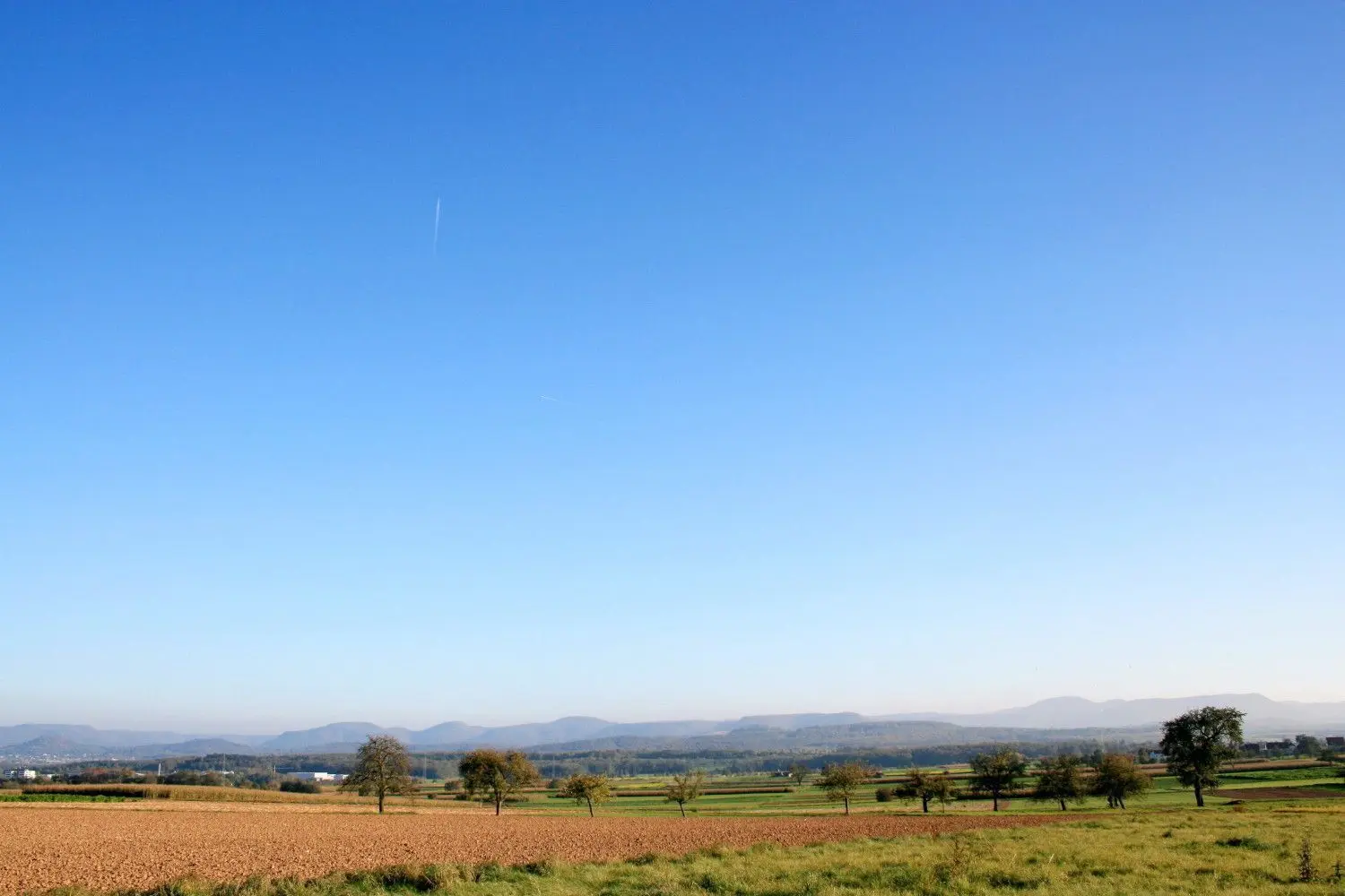 Wie eine Mauer mit weitem Himmel erscheint der Albtrauf aus Richtung Norden am Horizont.⇥