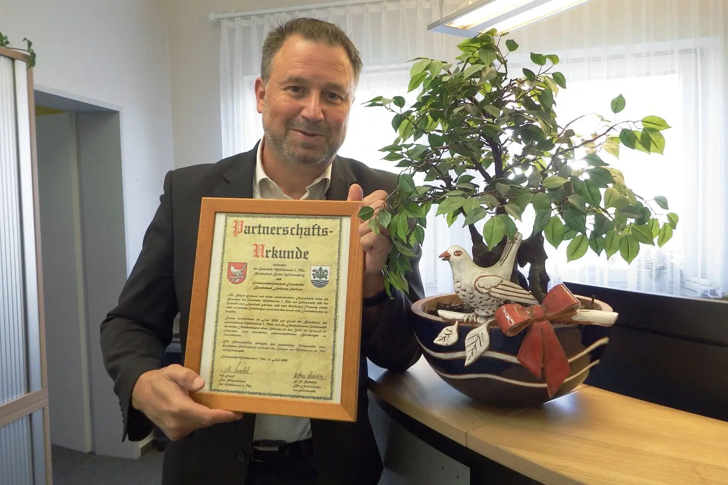 Stolz präsentiert Bernd Schaefer die Partnerschaftsurkunde aus dem Jahr 2001.