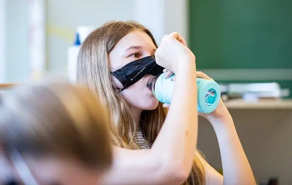 Eine Schülerin der Klasse 8a der Gesamtschule in Münster, hebt ihre Mund- und Nasenmaske an um etwas zu trinken.