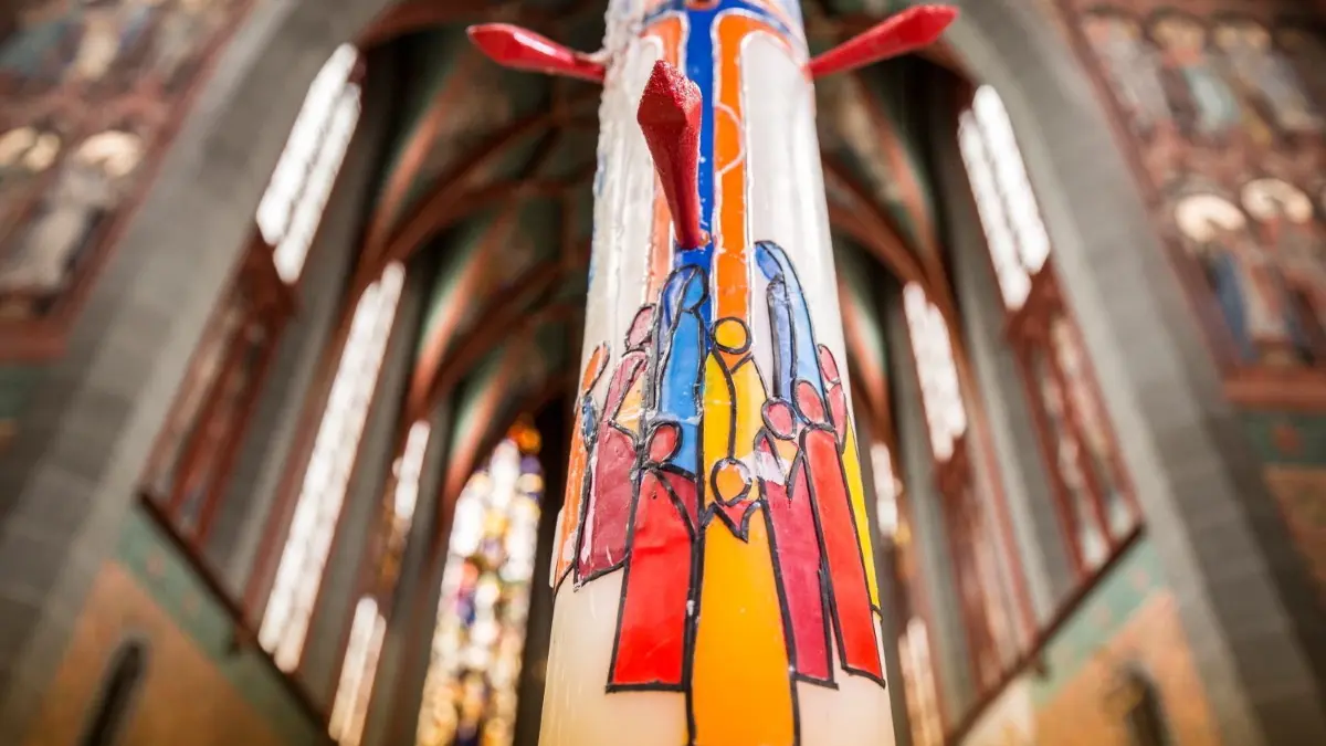 Die aktuelle Osterkerze von Helga Fricke in St. Georg: Die Künstlerin zeigt Frauen und Männer, die gleichberechtigt unter dem Kreuz stehen. ⇥
Georgskirche Osterkerze Frauen unterm Kreuz