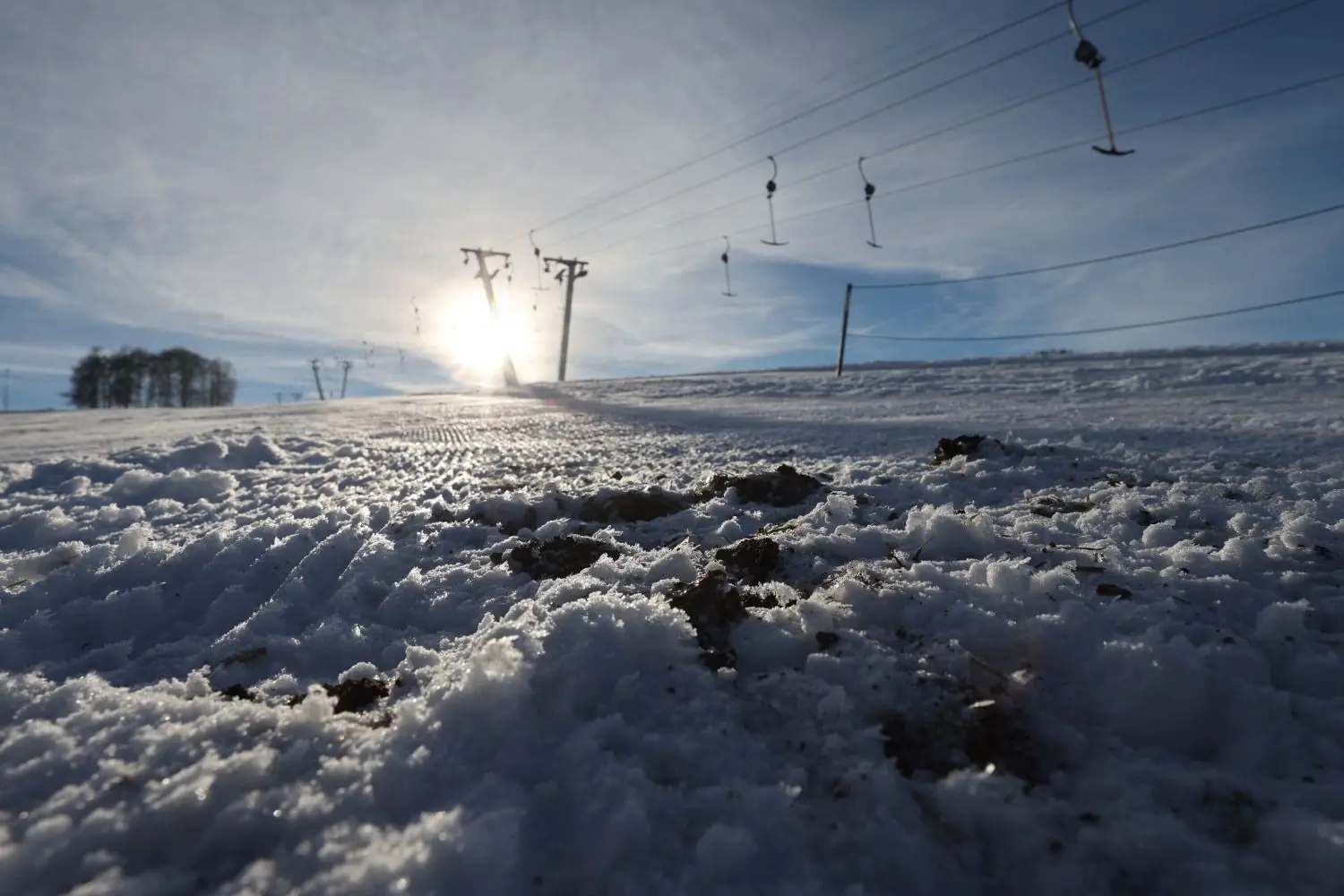 Hier und da sind Grasbüschel durch die dünne Schneeschicht am Skilift Salzwinkel in Zainingen zu sehen, der Lift ist dennoch offen und einige Besucher nutzen die noch leeren Hänge.