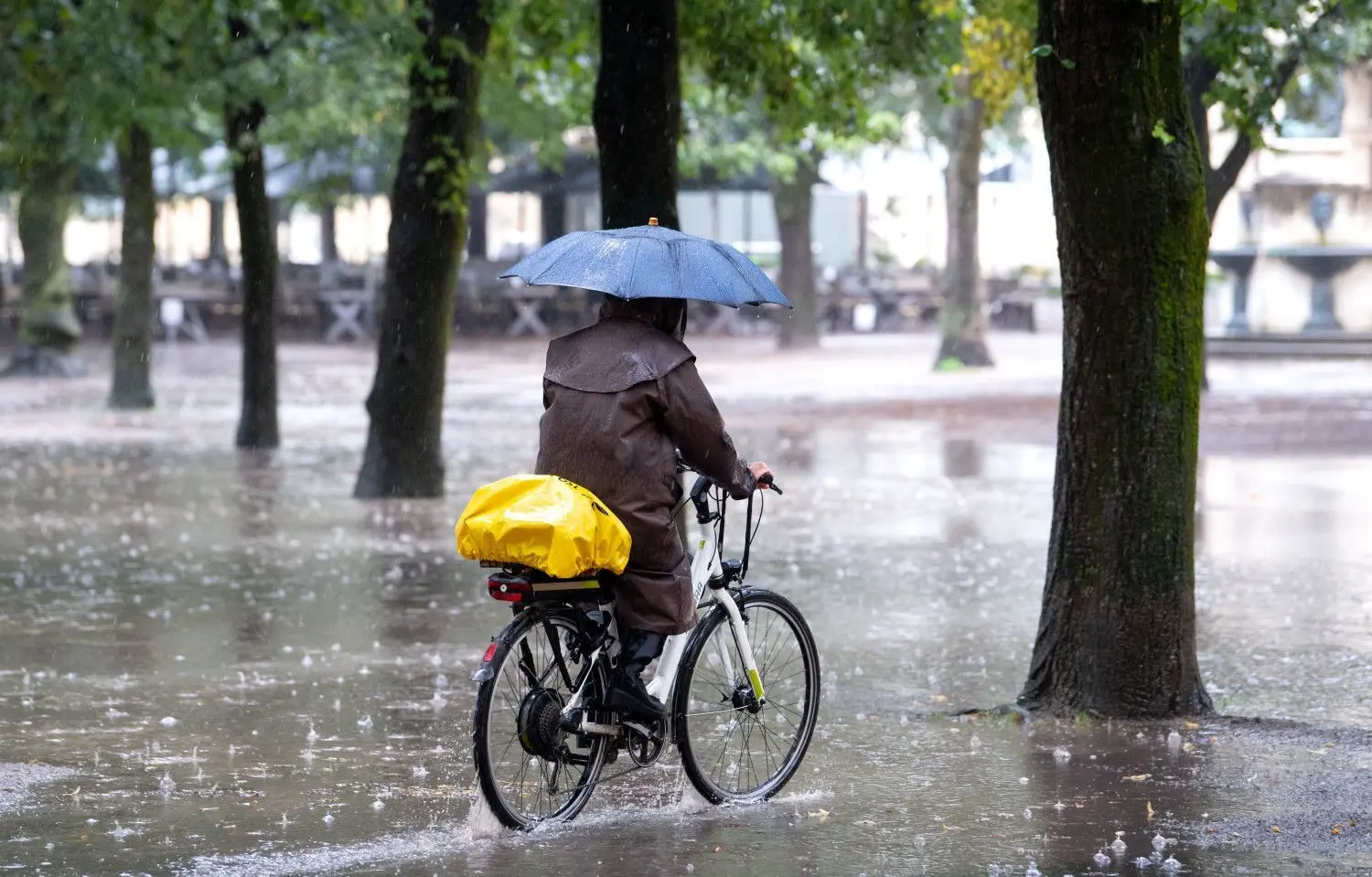 30. August 2021: Eine Frau fährt im Regen mit ihrem Fahrrad durch den Hofgarten in München.⇥