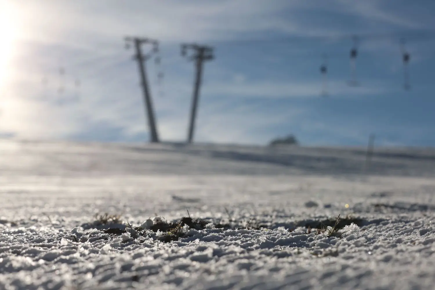 Hier und da sind Grasbüschel durch die dünne Schneeschicht am Skilift Salzwinkel in Zainingen zu sehen, der Lift ist dennoch offen und einige Besucher nutzen die noch leeren Hänge.