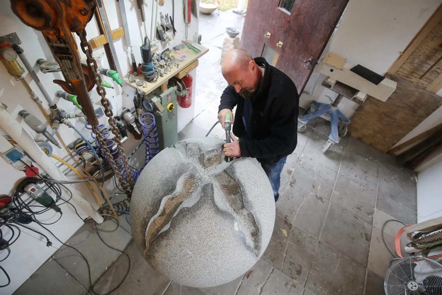 Bildhauer Konrad Schlipf bei der Arbeit: Die Granitkugel ist nicht heil und intakt, sondern mehrfach aufgerissen.