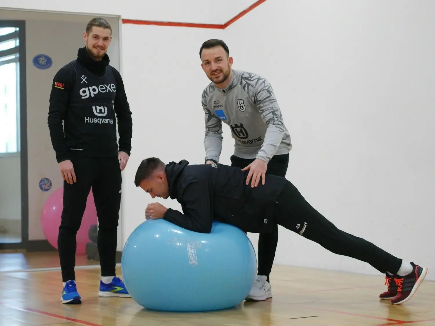 Athletiktrainer Christoph Zellner (r.) leitet Romario Rösch – im Unterarmstütz – und Dennis Chessa im Gymnastikraum des Hotels bei einer Übung an. ⇥