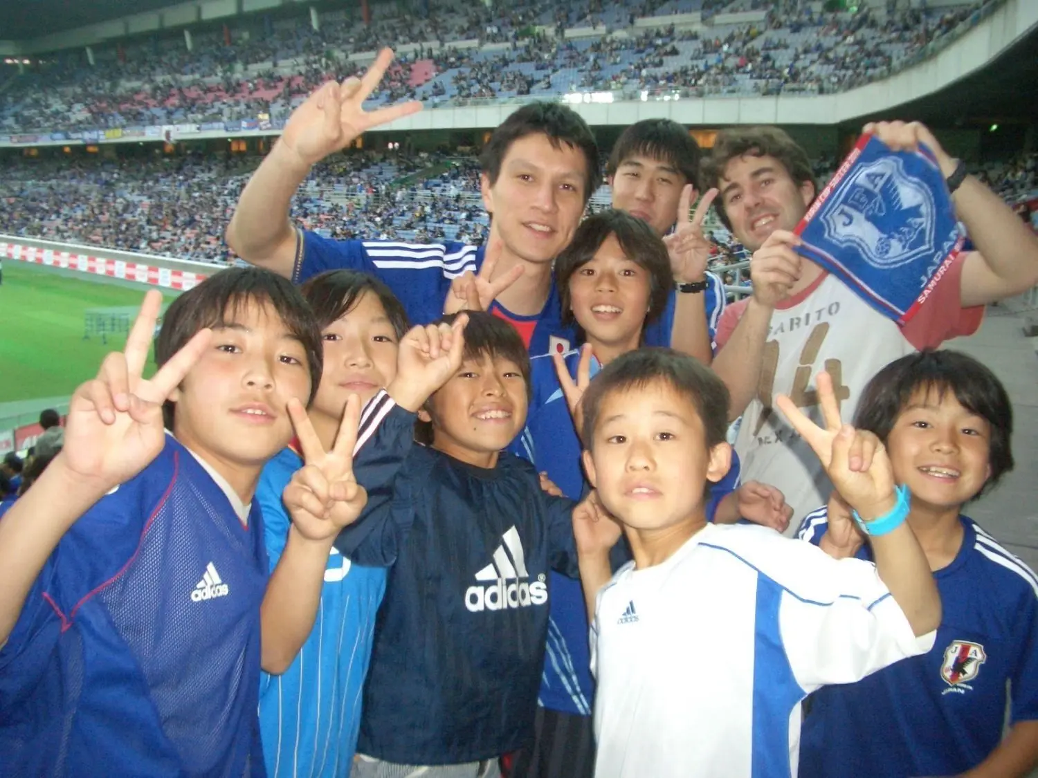 Drei Monate nach der Reaktorkatastrophe: Takuma Melber besucht gemeinsam mit einem japanischen und einem spanischen Freund das Fußball-Länderspiel Japan gegen Tschechen in Yokohama. „Diese begeisterte Gruppe japanischer Kinder wollte mit uns unbedingt dieses Foto machen.“ Die Partie endete übrigens 0:0. ⇥