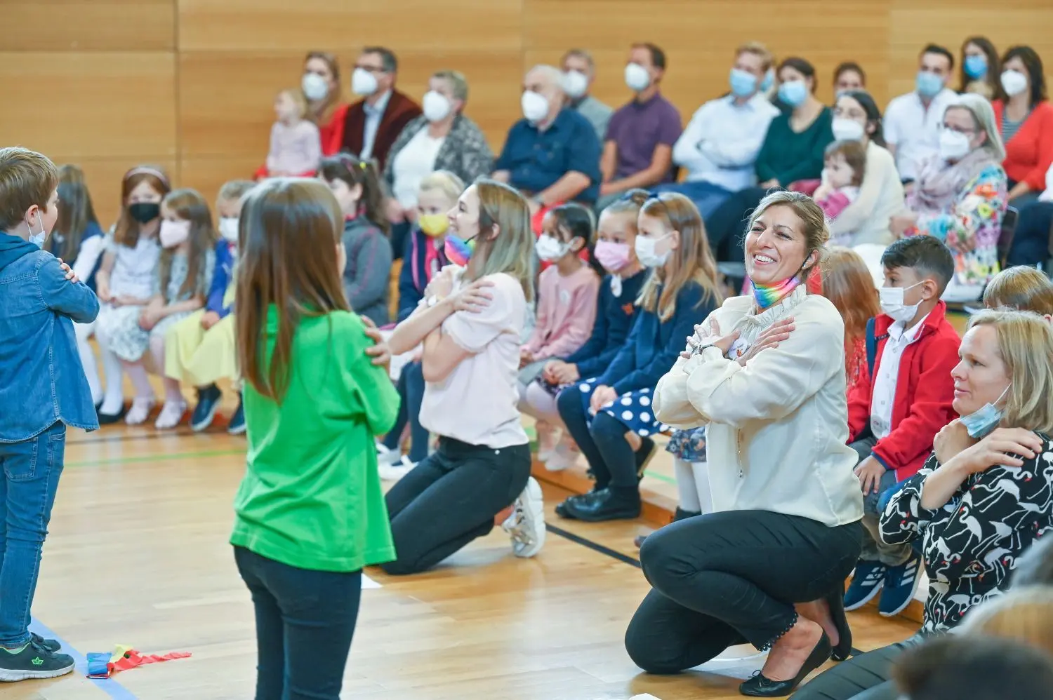 Die Feier zur Einschulung in der Turnhalle der Meinloh-Grundschule: Die Zweitklässler führen für die Erstklässler etwas auf, die zugucken dürfen, genauso wie Eltern und Großeltern. Lehrerin Isabel Vogel (mitte) und Sonderpädagogin Silke Brenner (rechts) sind mittendrin.