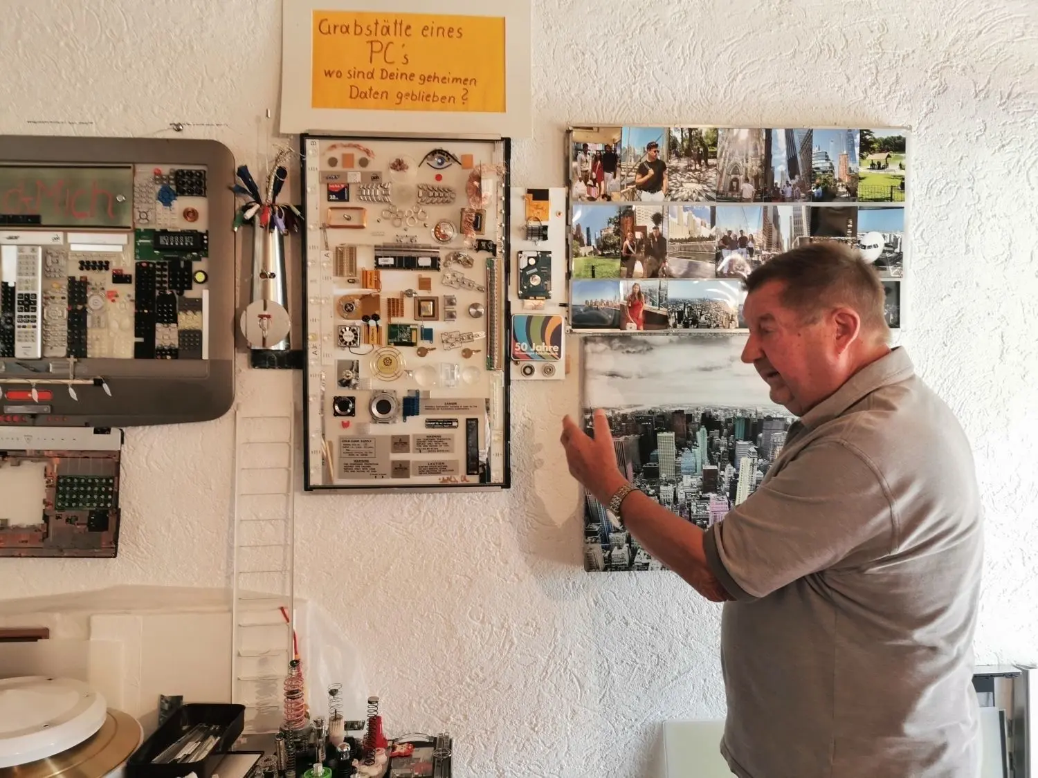In Helmut Schmids Garage hängen Kunstwerke aus Einzelteilen von Elektrogeräten. In der Mitte die „Grabstätte eines PCs“, mit einem Blumenstrauß aus Kabeln daneben.⇥