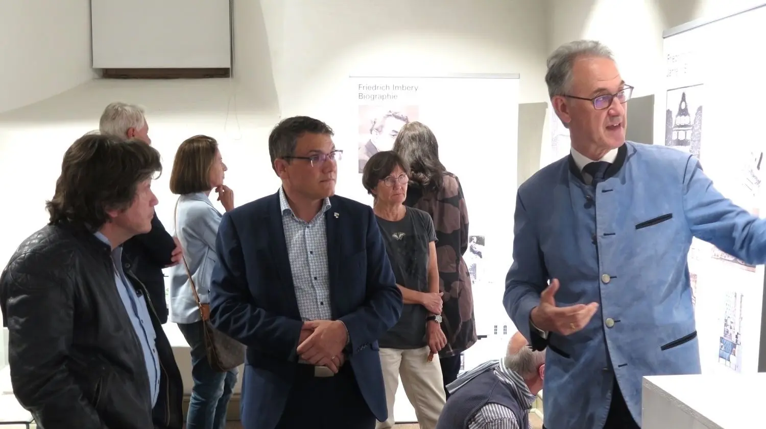 Kurator Franz-Severin Gäßler (rechts) erläuterte den Gästen – unter ihnen Oberbürgermeister Dirk Abel (Mitte) – bei einem Rundgang durch die Ausstellung die Bedeutung des Schulneubaus vor 100 Jahren aus architektonischer Sicht.
