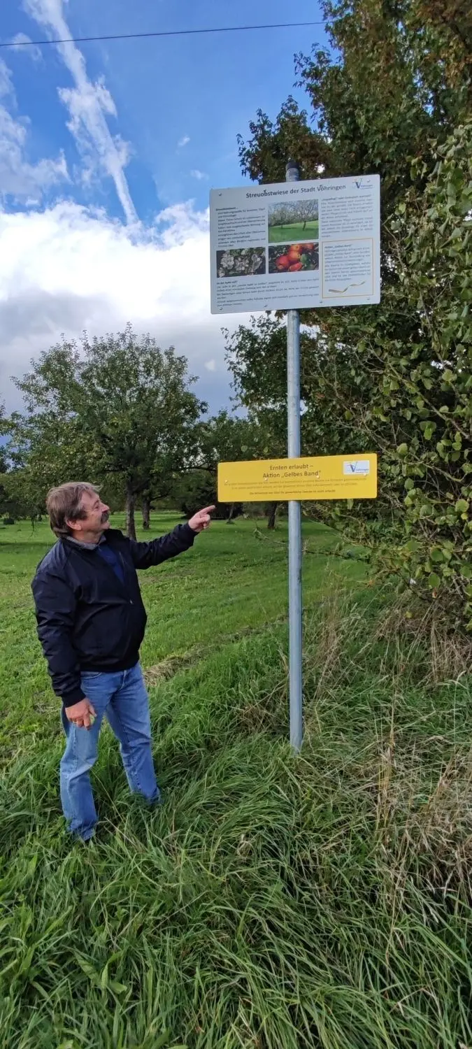 Herbert Walk, Vorsitzender des Vöhringer Obst- und Gartenbauvereins, zeigt auf die Schilder, die zum Obsternten einladen und auf die Bedeutung von Streuobstwiesen hinweisen. ⇥