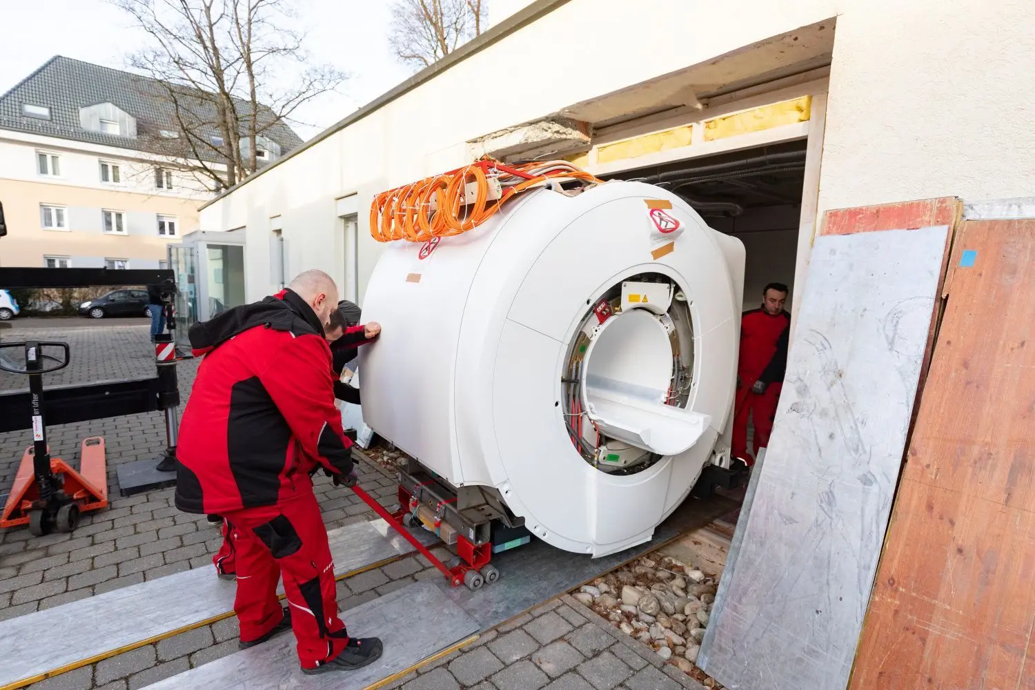 Millimeterarbeit: Das Team des Logistik-Unternehmens schiebt das MRT-Gerät vorsichtig in den Untersuchungsraum.