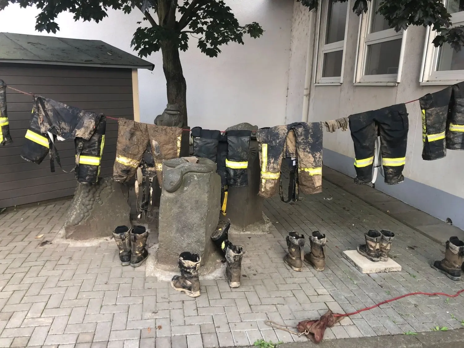 Auf einer provisorischen Wäscheleine hängt die schlammverschmierte Einsatzkleidung zum Trocknen für den nächsten Einsatztag.