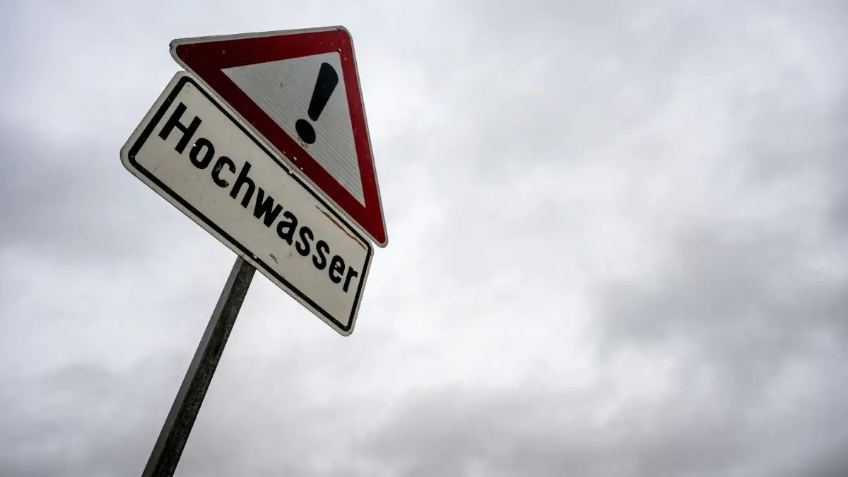 An Donau und Iller besteht die Gefahr von Hochwasser.
02.01.2024, Bayern, Hemmendorf: Ein Schild warnt vor Hochwasser, der Himmel über ihm verheißt weiteren Regen. Am Pegel Schenkenau soll in der Nacht zum 3. Januar erneut die Hochwasser-Meldestufe 3 erreicht werden. Foto: Pia Bayer/dpa +++ dpa-Bildfunk +++