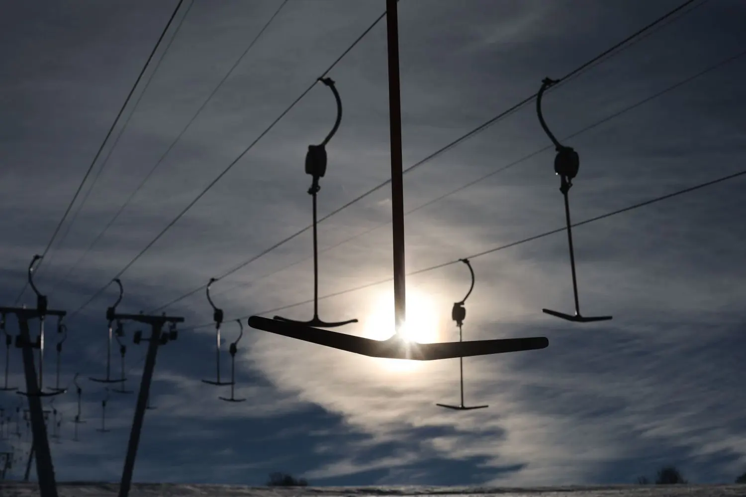Hier und da sind Grasbüschel durch die dünne Schneeschicht am Skilift Salzwinkel in Zainingen zu sehen, der Lift ist dennoch offen und einige Besucher nutzen die noch leeren Hänge.