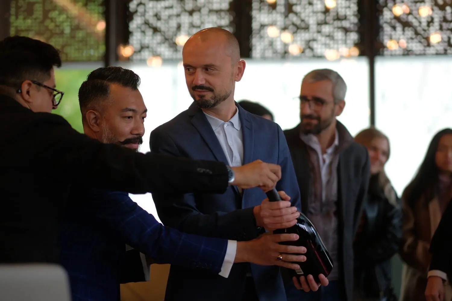 Storemanager Alexander di Renzo (Mitte) öffnet die erste Flasche.