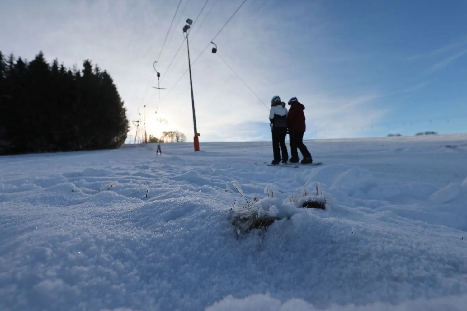 Hier und da sind Grasbüschel durch die dünne Schneeschicht am Skilift Salzwinkel in Zainingen zu sehen, der Lift ist dennoch offen und einige Besucher nutzen die noch leeren Hänge.
