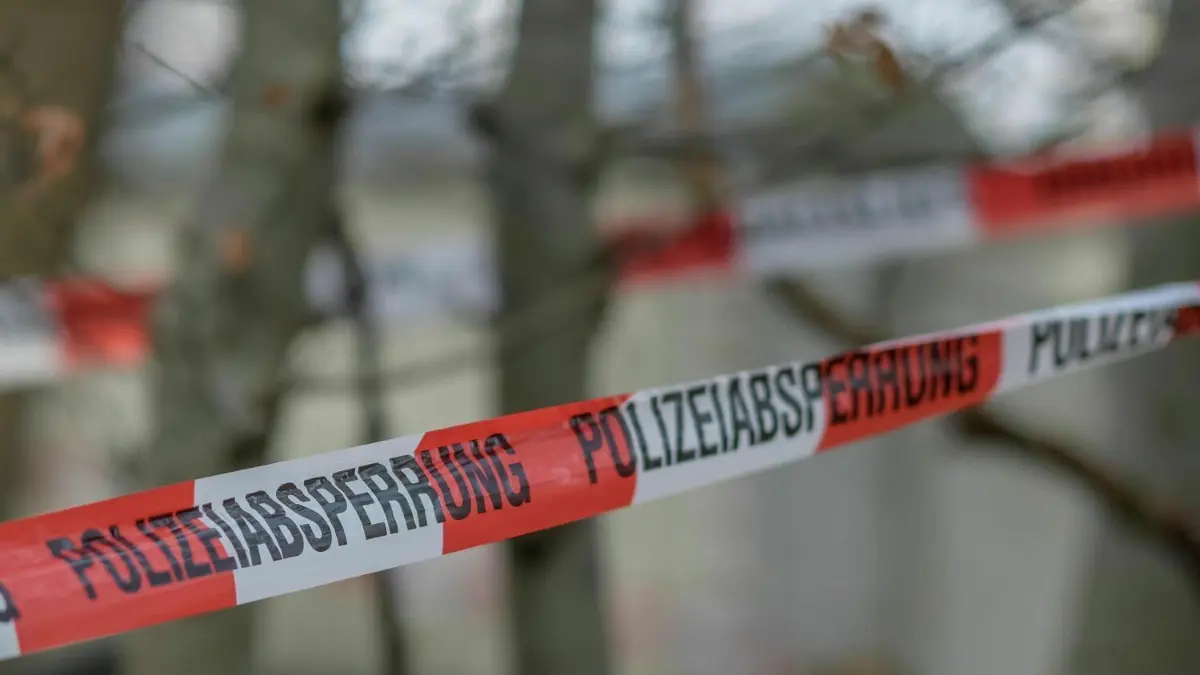 Tatort abgesperrt: Mit Flatterband sichert die Polizei potenzielle Tatorte, an denen Tote gefunden wurden, die vermutlich durch eine unnatürliche Ursache starben. (Symbolbild)
Ein Flatterband der Polizei ist als Absperrung um mehrere Bäume in einem Waldstück gewickelt, an dem auch ein Bauwagen und eine Holzhütte stehen. In dem Wald bei Seevetal in Niedersachsen sind in einem Erddepot möglicherweise Hinterlassenschaften der linksterroristischen RAF gefunden worden. +++ dpa-Bildfunk +++