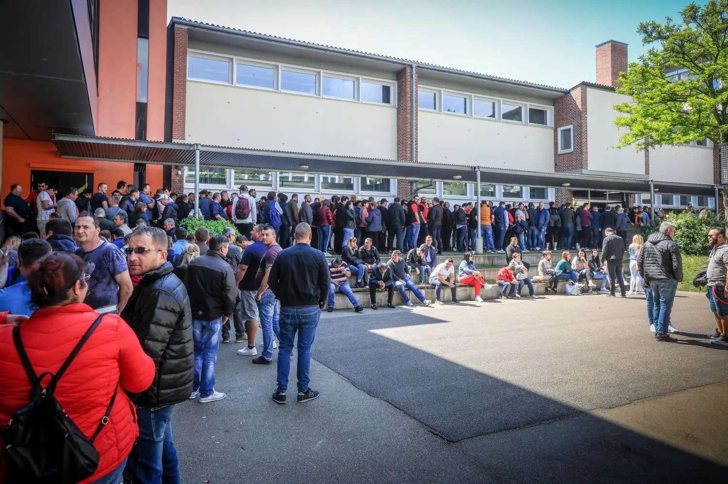 Vor dem Wahllokal im Ulmer Kepler Gymnasium hat sich momentan ein Menschenauflauf gebildet. Offenbar sind rumänische Wähler sauer über die langen Wartezeiten.