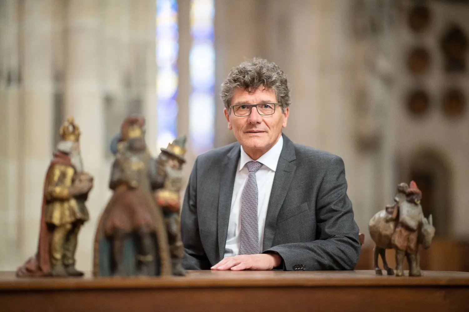 Ernst-Wilhelm Gohl, Dekan des evangelischen Kirchenbezirks Ulm, sitzt im Ulmer Münster hinter den Figuren der Heiligen Drei Könige.