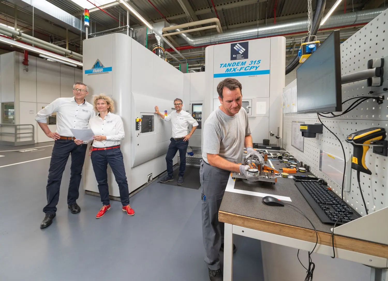 So sieht eine moderne Zerspanungsanlage aus: Mechaniker Kai Sielka prüft ein Bauteil, das aus der Maschine kam, mit einer Messuhr. Mit im Bild (von links): Werkleiter Claus Schmid, Werkleiterin Nicolet Eglseder und Fertigungsleiter Daniel Becker.