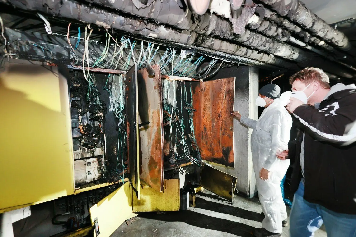 Rüdiger Gaukel vom gleichnamigen Elektro-Unternehmen begutachtet mit einem Arbeiter vom Schadenservice Kilic am Dienstag die Brandstelle. Der ganze Raum muss gesäubert werden, bevor die verbrannten Leitungen erneuert werden.⇥