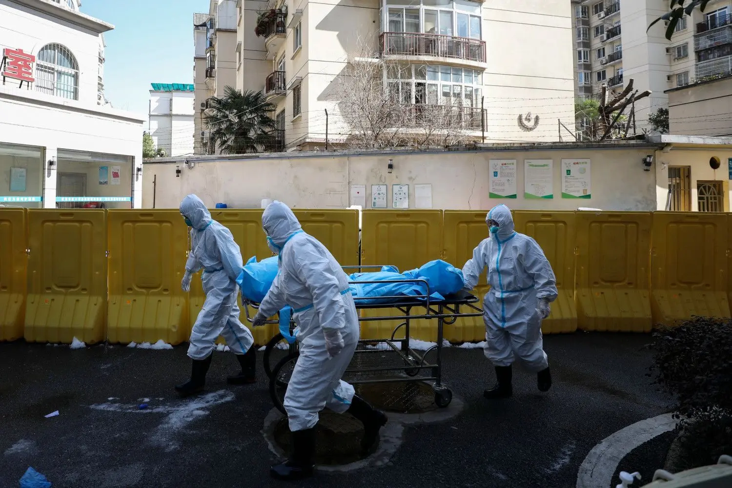 Wuhan im Februar 2020: Medizinische Mitarbeiter transportieren einen in einer Klinik an Corona Verstorbenen. ⇥