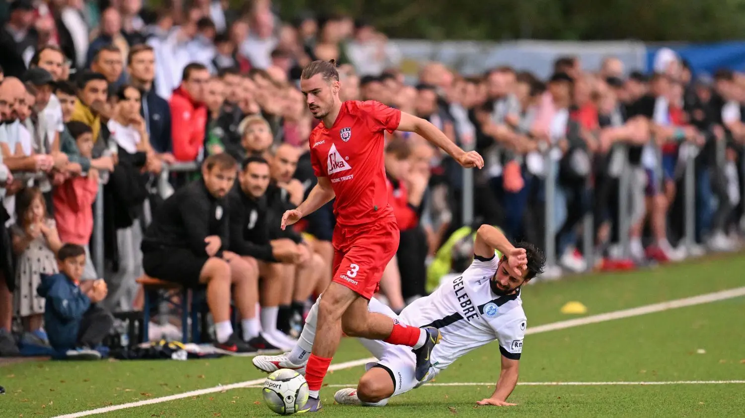 Kampf um jeden Meter Boden vor vollen Rängen auf dem Kunstrasenplatz im Sportpark Markwasen: SSV-Abwehrspieler Nils Staiger (links, rote Spielkleidung) wird hier von Young-Boys-Akteur Kevin Nicolaci attackiert.⇥
