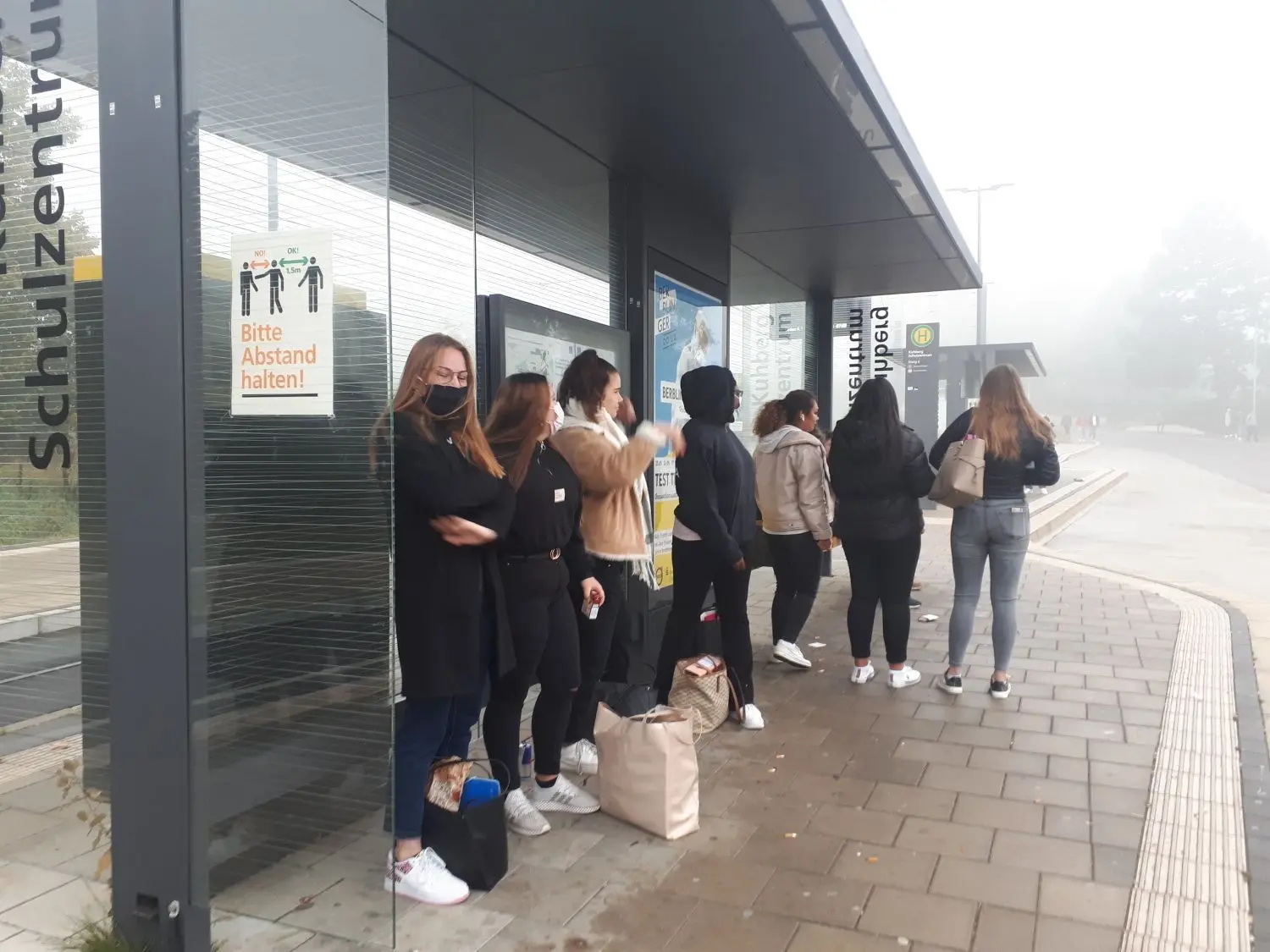 Schülerinnen treffen sich an der Bushaltestele vor dem Unterricht. ⇥