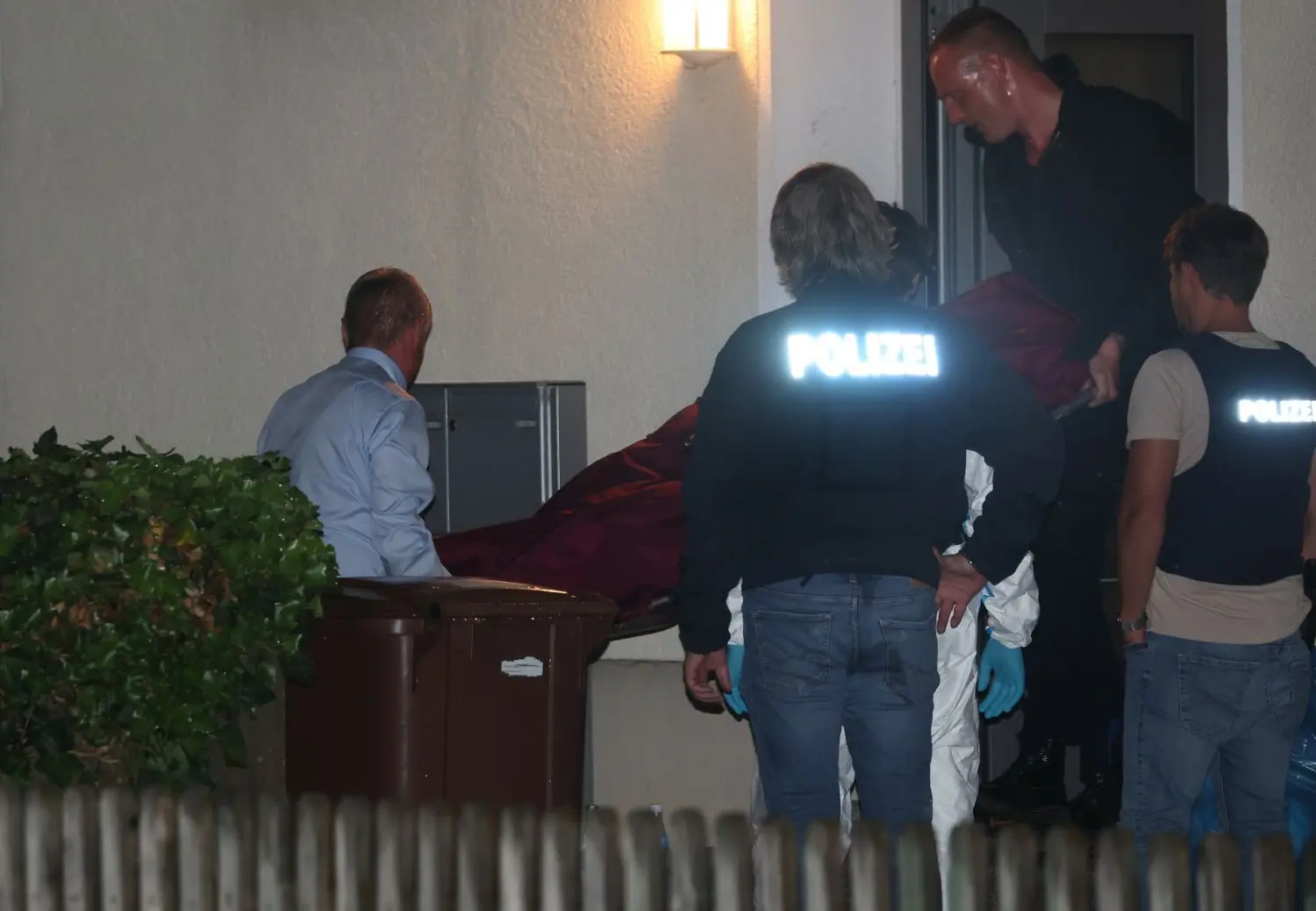 Eine der Leichen wird aus dem Mehrfamilienhaus in Langweid bei augsburg getragen, in dem drei Menschen erschossen wurden. Der mutmaßliche Täter ist Sportschütze. Bei ihm wurden mehrere Waffen gefunden.
