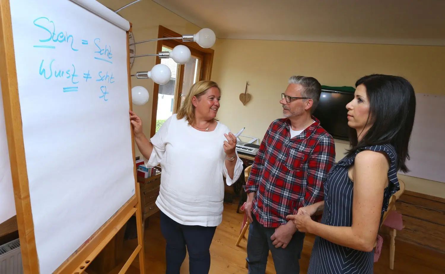 Ariane Willikonsky (links) steht in der Allgäuer Sprachschule mit ihren Schülern, dem Mediengestalter Markus Zieris und der Verkaufstrainerin Rita Katharina Biermeier, während eines Hochdeutschkurses.