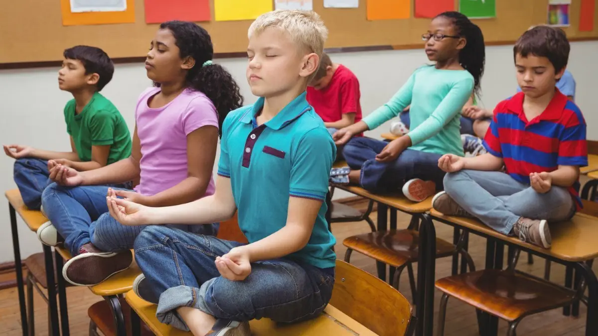 Yoga im Klassenzimmer.
Kinder, Schule, Yoga/Kinder sitzen auf den Tischen in der Schule im Yoga-Sitz. Download am 21.07.2022 für Kostenstelle SHO011013, Südwest Presse Hohenlohe Foto: © WavebreakmediaMicro/adobe.stock.com