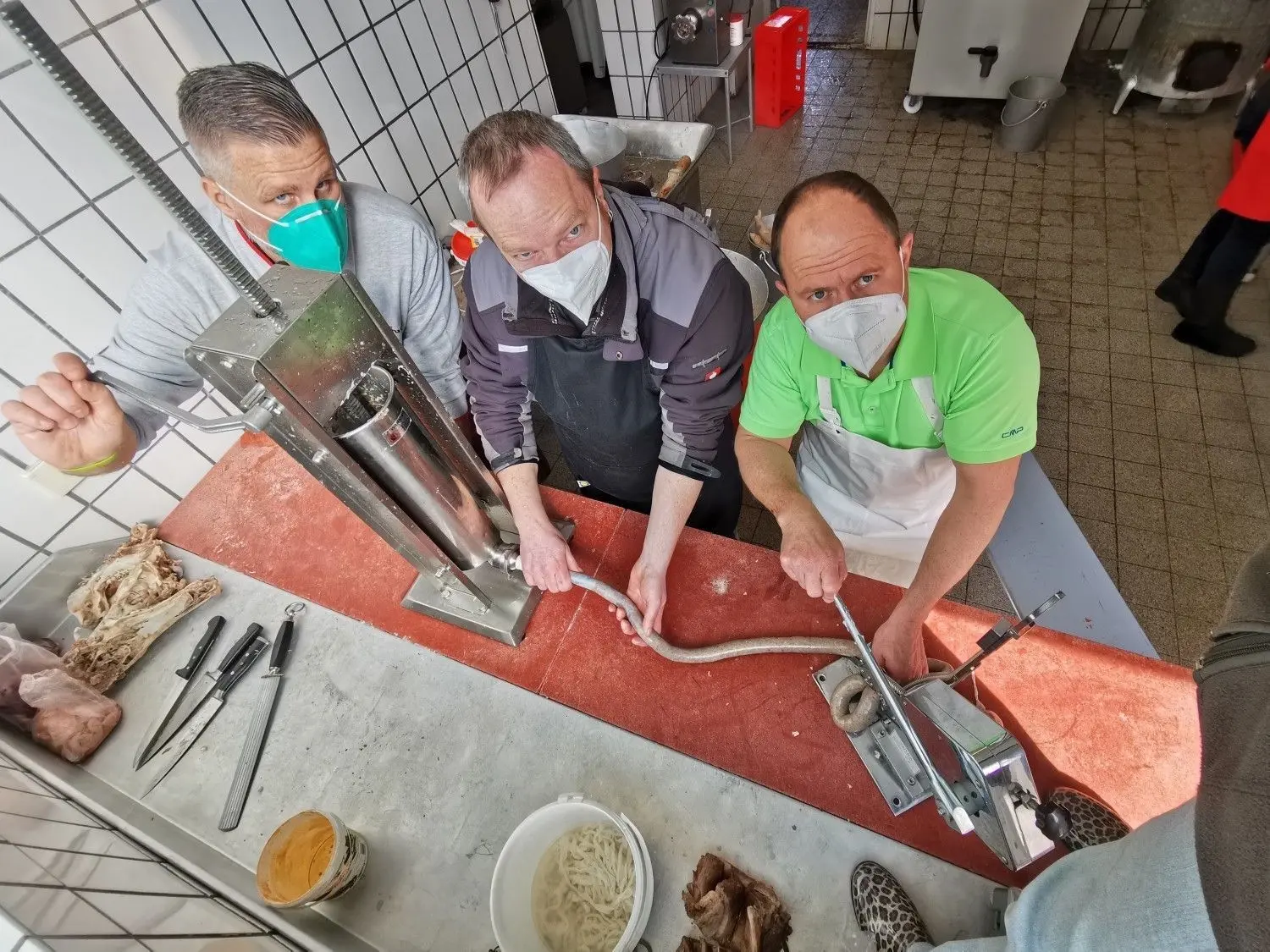 Drei Männer aus dem VHS-Kurs „Von der Sau zur Wurst“ am Wurstfüller. ⇥