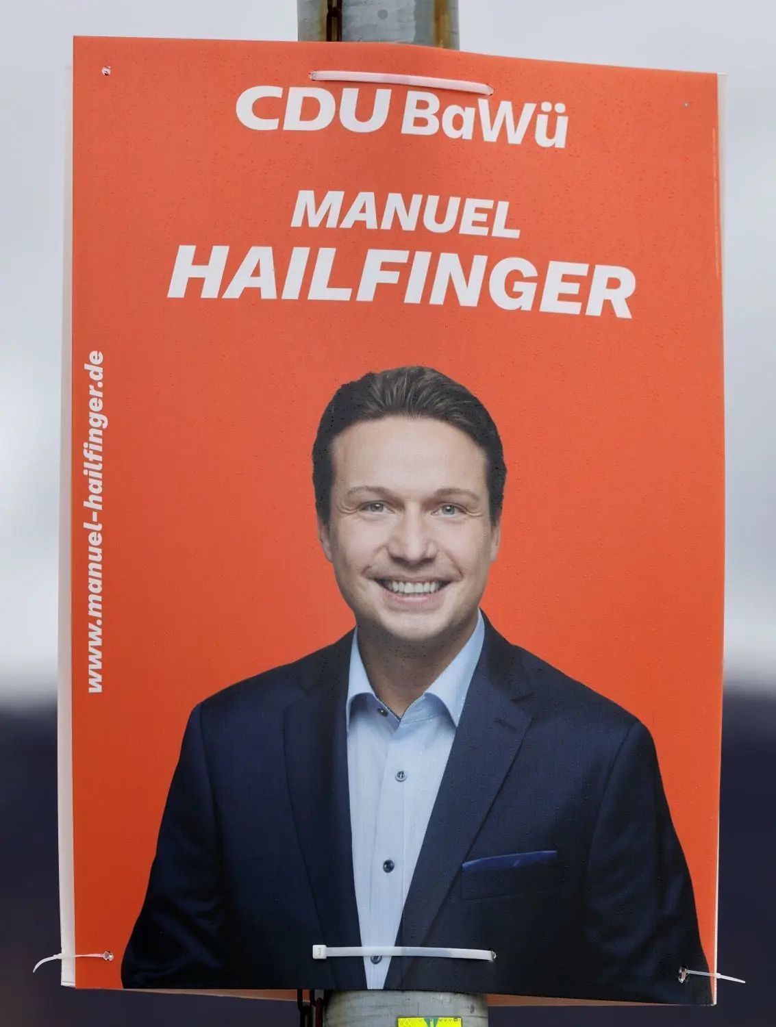 Manuel Hailfinger strahlt für die CDU vor knalligem Orange vom Plakat herab.⇥