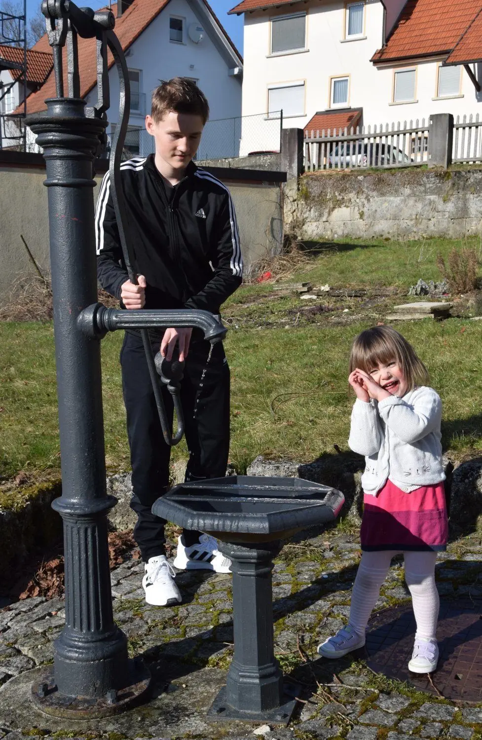David Clauß und Meike Christenson zapfen Wasser an der alten Schwengelpumpe im Wittlinger Pfarrgarten. ⇥