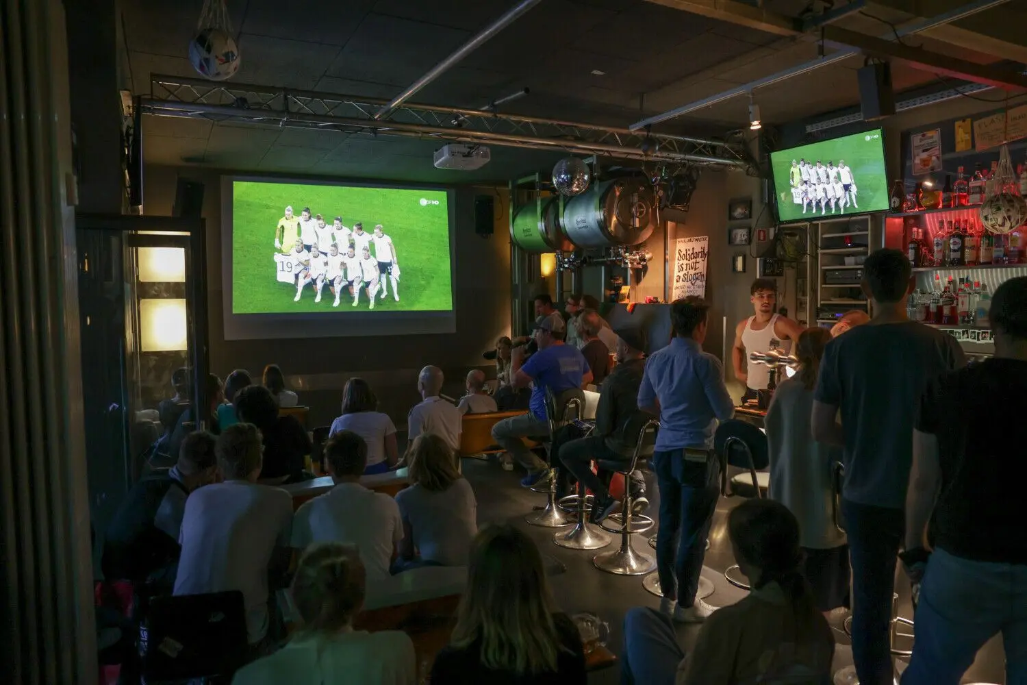 Um die Weltmeisterschaft in Katar mit anderen in einer Bar verfolgen zu können, muss man erst einmal eine Bar finden, die die Partien überträgt. Viele Gastwirte boykottieren die WM. Das Foto zeigt die Übertragung des Halbfinals der Frauen-EM. ⇥